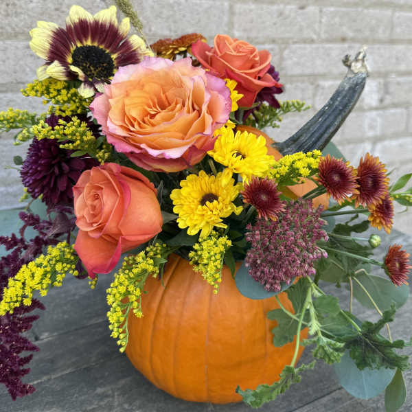 Fall bouquet in a pumpkin with roses and chrysanthemums