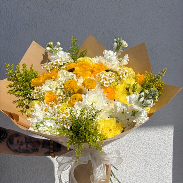 Yellow and white mixed bouquet wrapped in brown paper