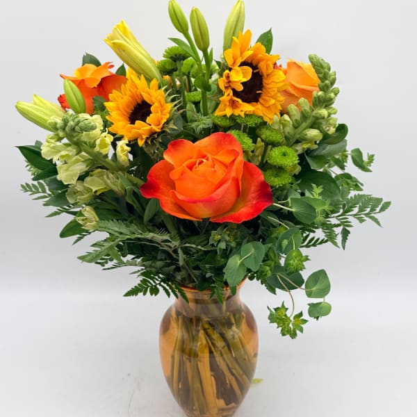 Orange rose and sunflowers in an amber glass vase