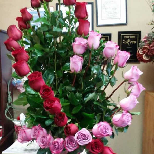 Tall arrangement of red and pink roses in a glass vase