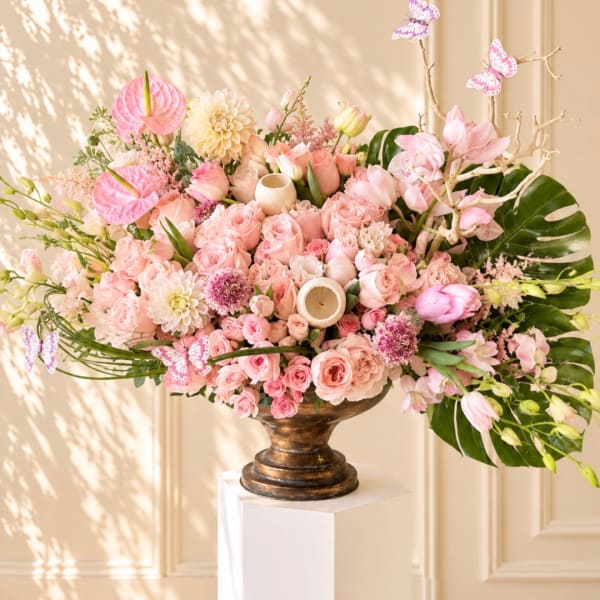 Large pink floral arrangement in a bronze pedestal vase