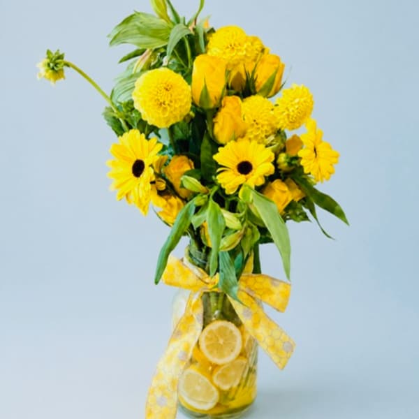 Yellow flower arrangement in a glass vase with a yellow ribbon