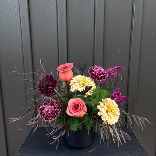Pink roses and cream flowers arranged in a black vase