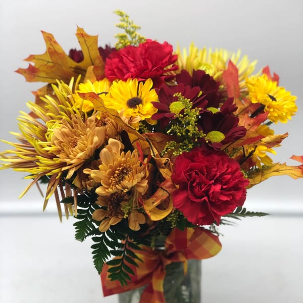 Autumn bouquet of red, yellow, and orange flowers in a glass vase