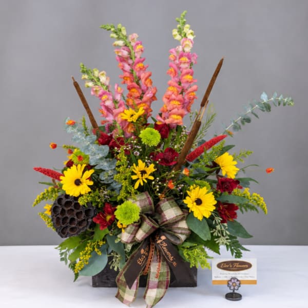 Mixed bouquet with pink snapdragons, yellow daisies, and a plaid ribbon in a black container