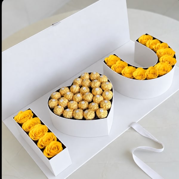 Yellow roses and gold-wrapped chocolates arranged in white gift boxes
