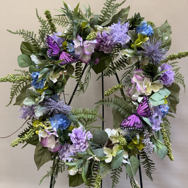 Purple and blue floral wreath with butterflies on a stand