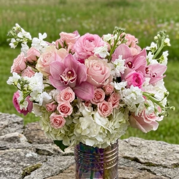 Pink roses and orchids arranged in a vase with white flowers