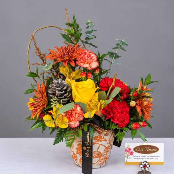 Colorful mixed flower arrangement in a patterned pot with a ribbon