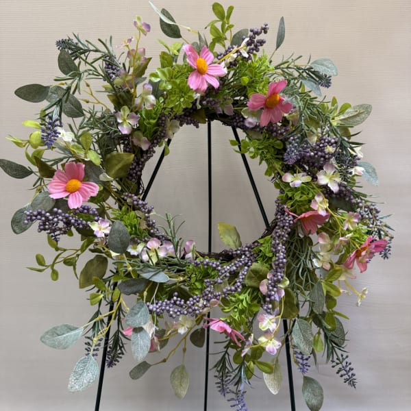 Floral wreath with pink daisy-like flowers and purple berries on a black stand