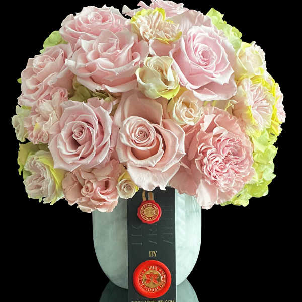 Pink rose bouquet in a pale blue vase with a black ribbon tag