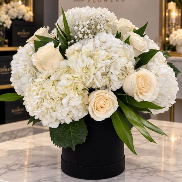 White hydrangea and cream rose arrangement in a black box