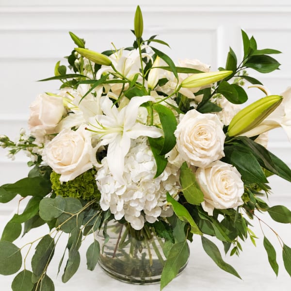 White roses and lilies arranged in a glass vase