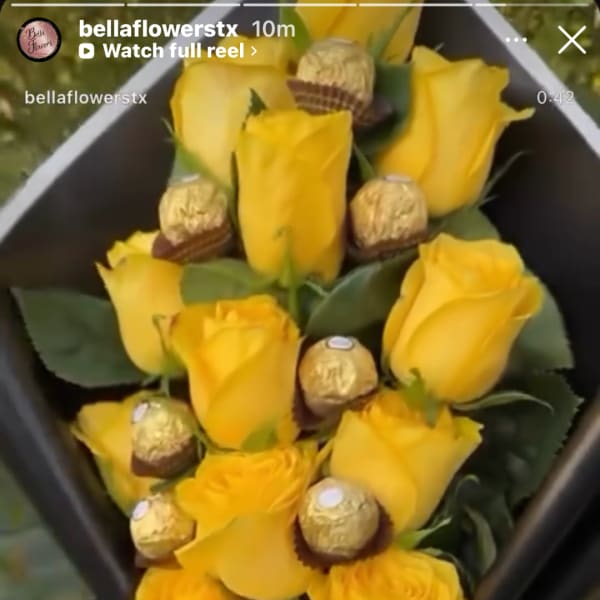 Yellow roses arranged with gold-wrapped chocolates in a black box