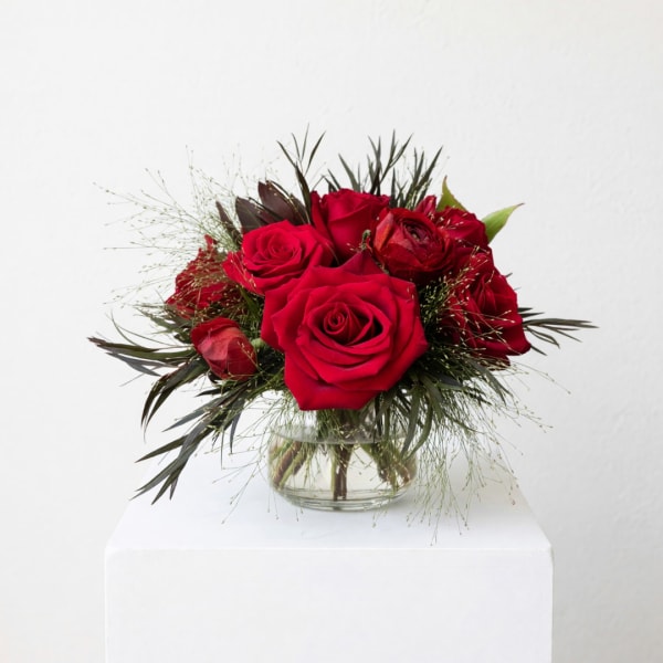 Red roses arranged in a clear glass vase