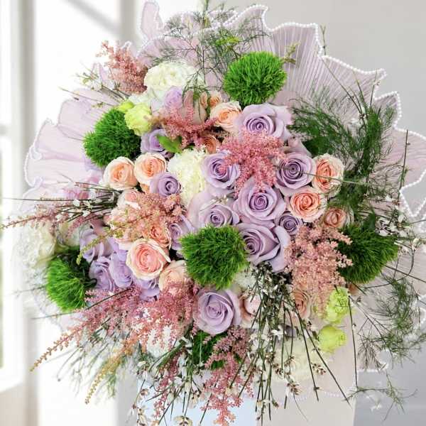 Bouquet of lavender and peach roses with green pom-pom accents