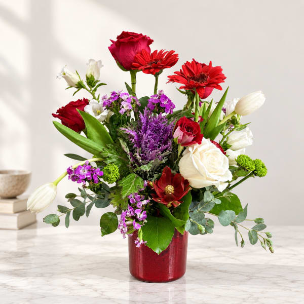 Mixed bouquet of red, white, and purple flowers in a red vase