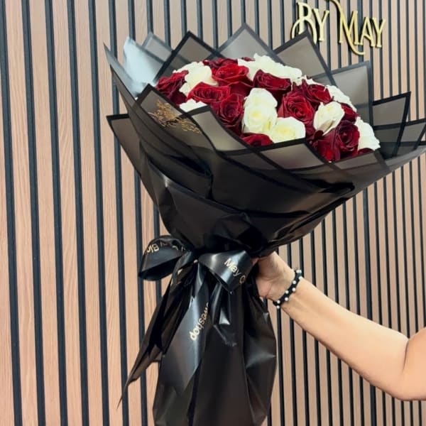 Bouquet of red and white roses wrapped in black paper