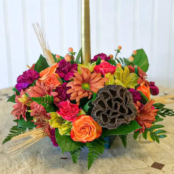 Colorful floral centerpiece with a tall gold taper candle