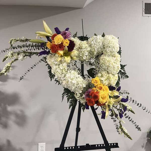 Large floral heart on an easel with white hydrangeas and colorful roses