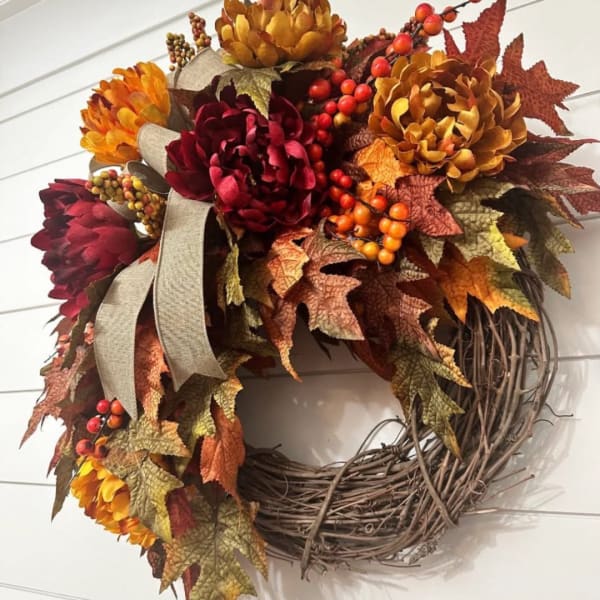 Autumn wreath with burgundy and gold flowers on a grapevine ring