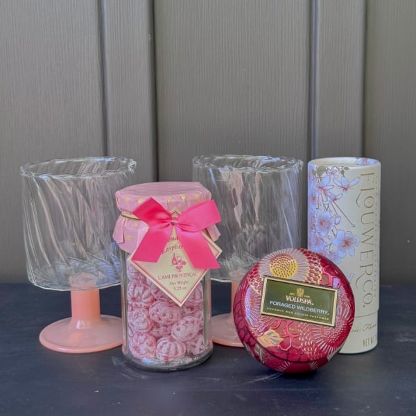 Assorted floral candles and two clear glass holders on a dark surface