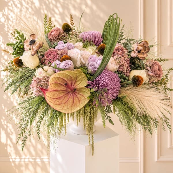 Large pastel floral arrangement in a white vase on a pedestal