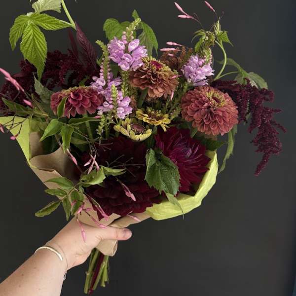 Handheld bouquet of burgundy, pink, and lavender flowers