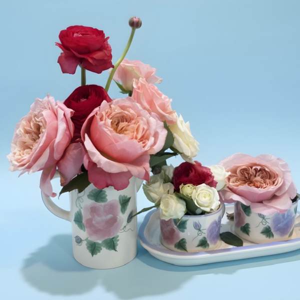 Pink and red roses arranged in floral mugs and a tray