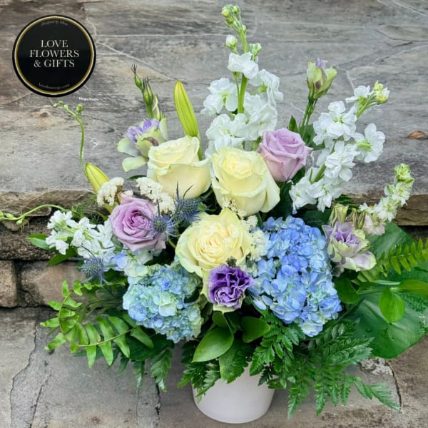 Pastel roses, hydrangeas, and white stock in a white vase