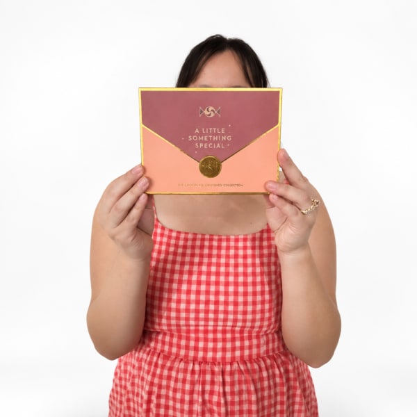 Person holding a boxed chocolate gift set in pink and peach packaging