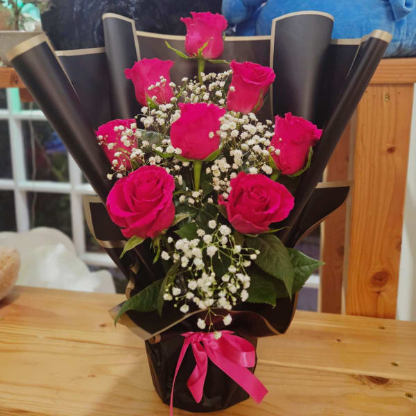 Bouquet of hot pink roses with white baby's breath in black wrap