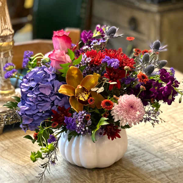 Colorful mixed flower arrangement in a white pumpkin vase