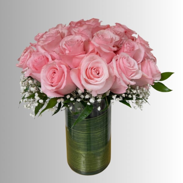 Pink roses arranged in a tall glass vase with white filler flowers