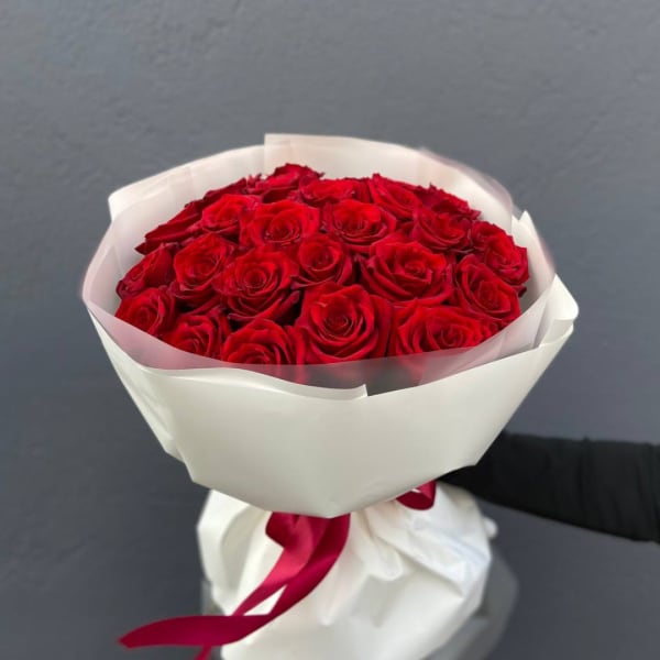 Bouquet of red roses wrapped in white paper with a red ribbon