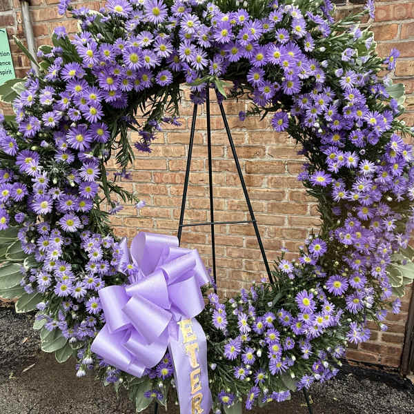 Purple daisy wreath on a black easel with a lavender ribbon bow