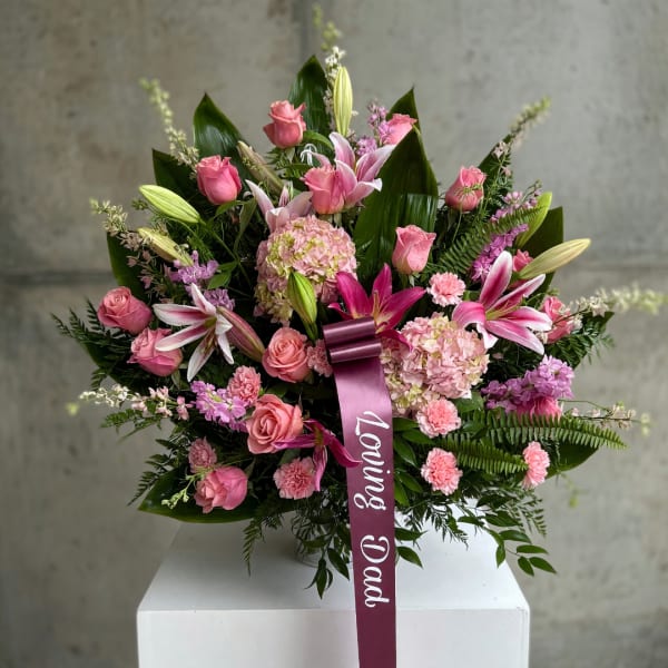 Pink roses and lilies arranged with hydrangeas and a ribbon reading Loving Dad