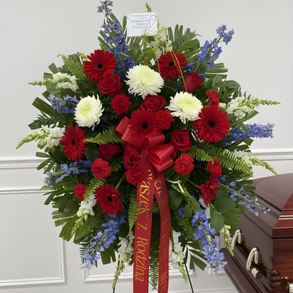 Large red, white, and blue funeral spray beside a casket