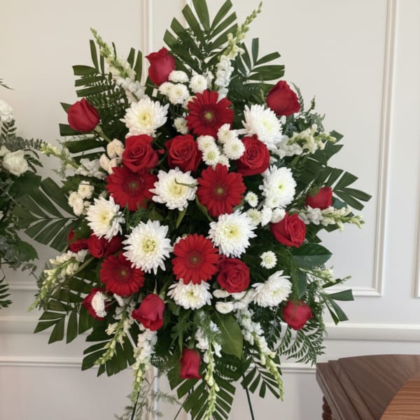 Red roses and white chrysanthemums arranged with red gerbera daisies in a standing spray