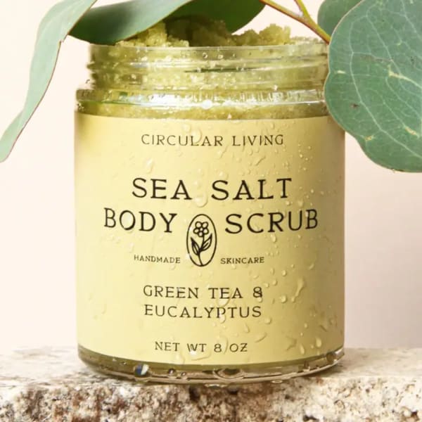 Jar of sea salt body scrub with eucalyptus leaves around it