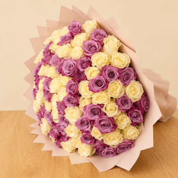Bouquet of purple and pale yellow roses wrapped in pink paper