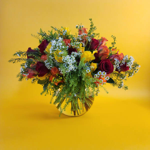 Mixed bouquet of roses and small white flowers in a round vase