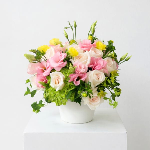 Pink and white roses with yellow blooms in a white vase