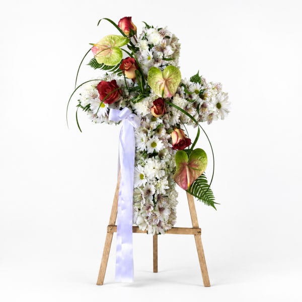 Cross-shaped floral easel spray with white blooms, red roses, and a lavender ribbon