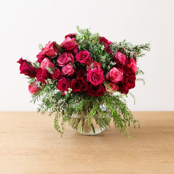 Pink and red roses arranged in a clear glass vase
