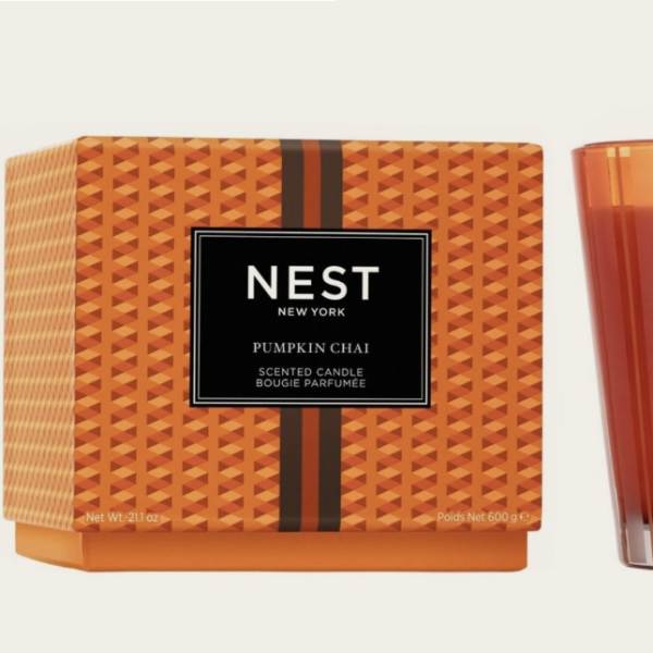 Pumpkin chai scented candle in an orange glass tumbler beside its box