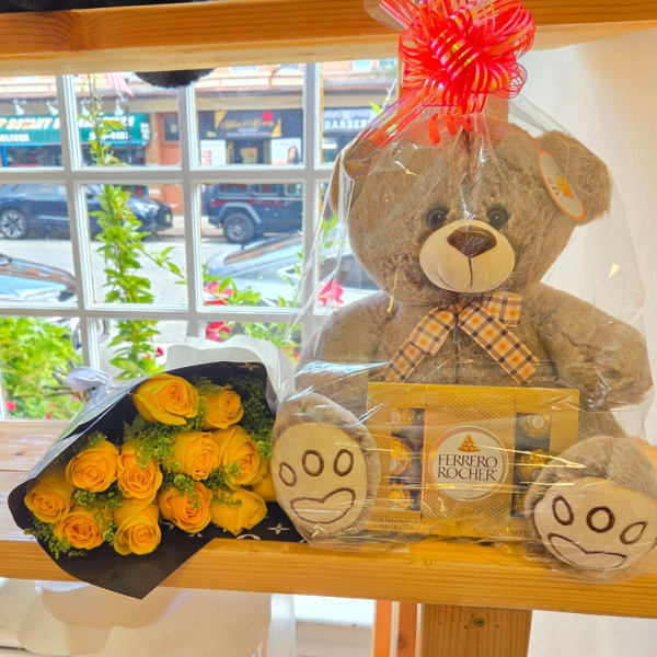 Yellow rose bouquet beside a teddy bear and Ferrero Rocher chocolates