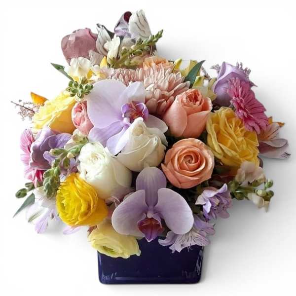 Mixed bouquet of pastel roses, orchids, and daisies in a dark vase