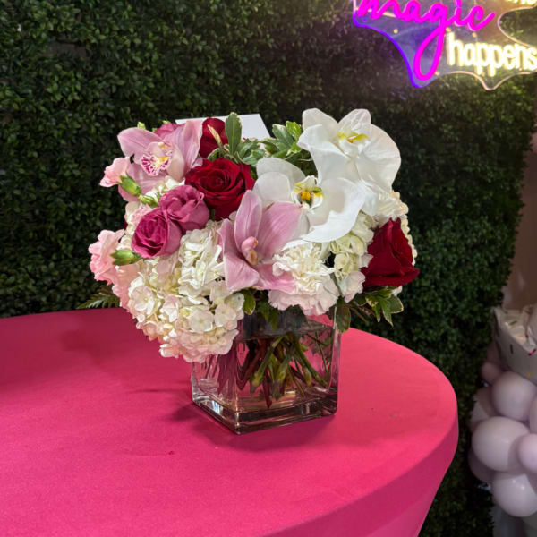 Pink and white floral arrangement in a clear square vase