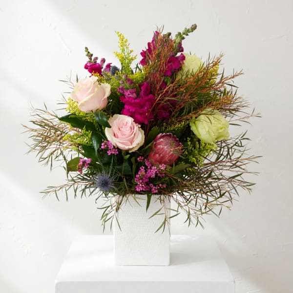 Mixed bouquet of pink and green flowers in a white vase